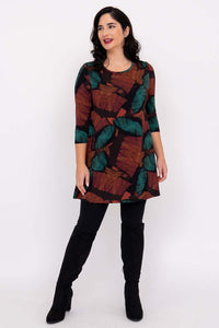 Full-length view of woman in autumn leaf print tunic, paired with leggings and boots