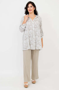 Woman wearing a full-length bamboo-linen tunic, hand touching collar, relaxed pose