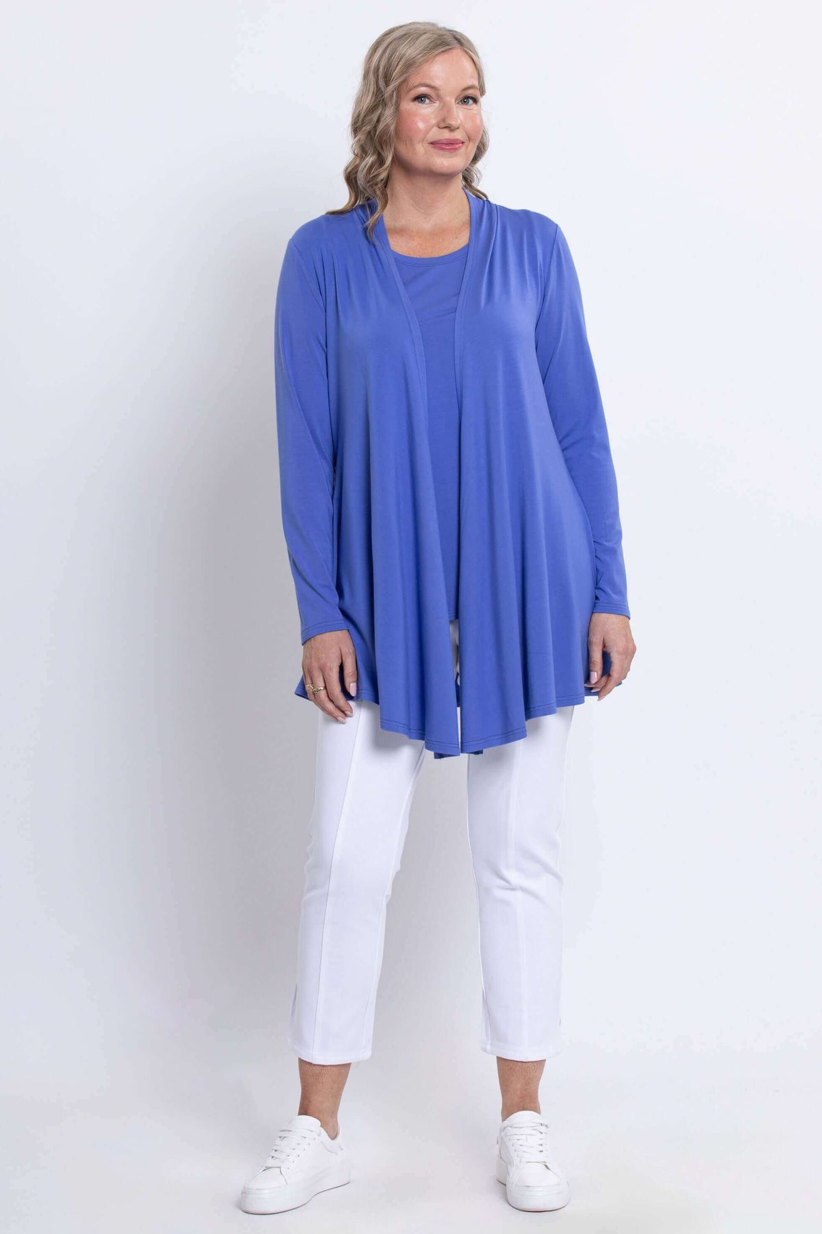 Full-length image of a woman in a blue long sleeve open front jacket paired with white pants