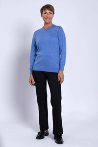 Woman standing in blue Merino V-neck sweater, full-length view