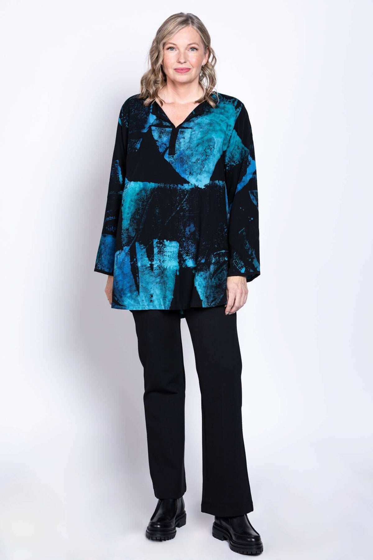 Woman standing front-facing in Kary Blouse, blue and black print, paired with black pants and boots