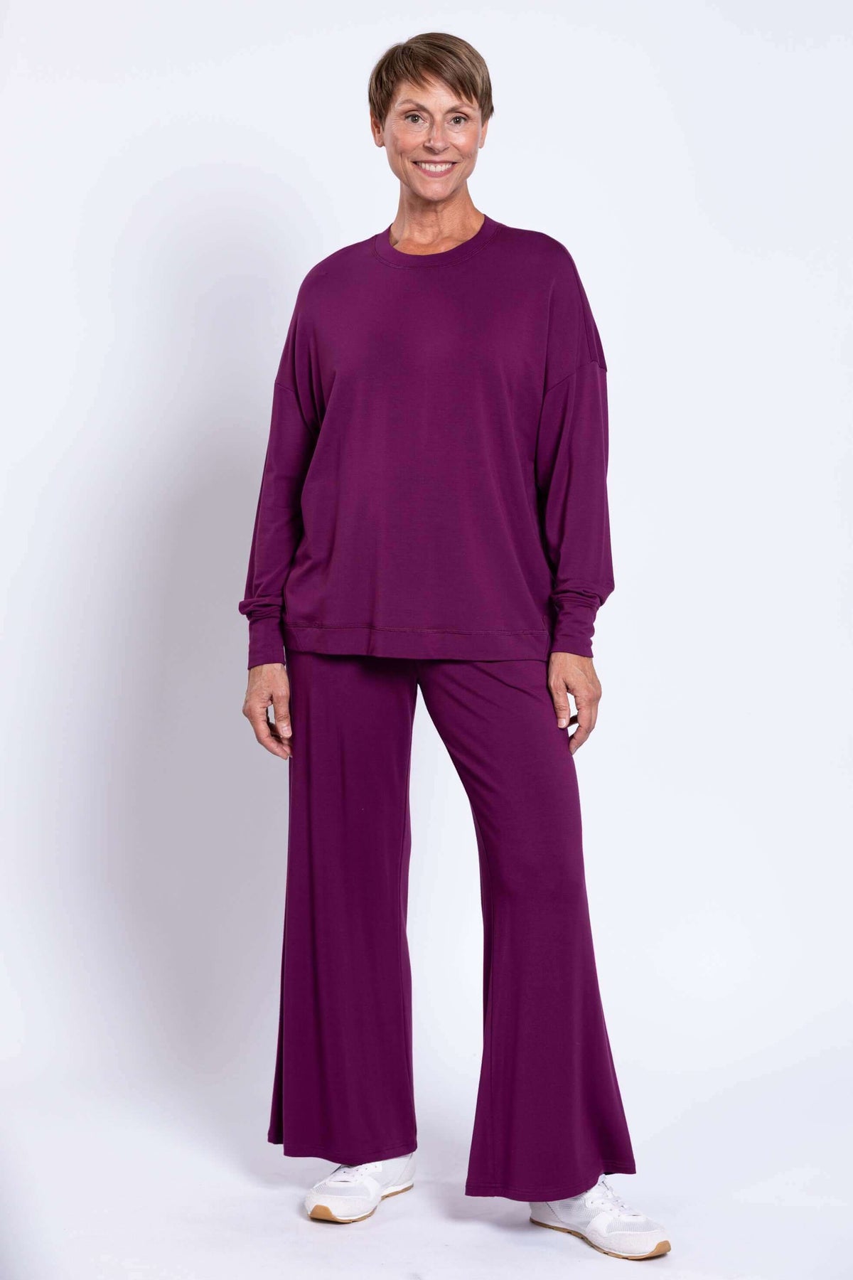 Full-length view of a woman in matching purple crew neck top and wide-leg pants