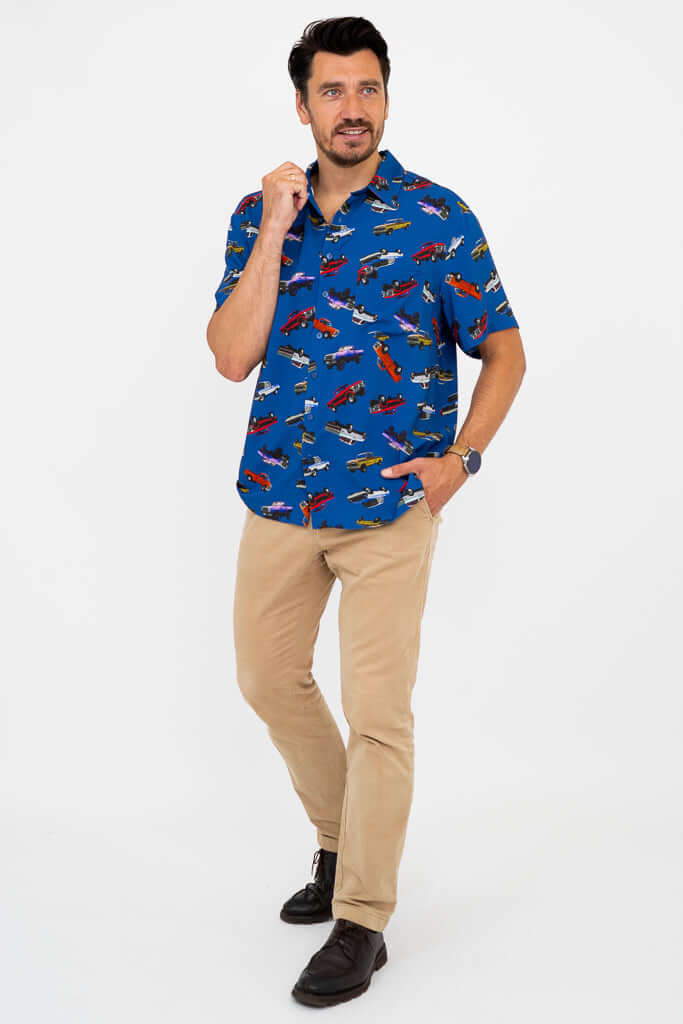 Full-length man in blue monster truck shirt and tan pants, hand on collar