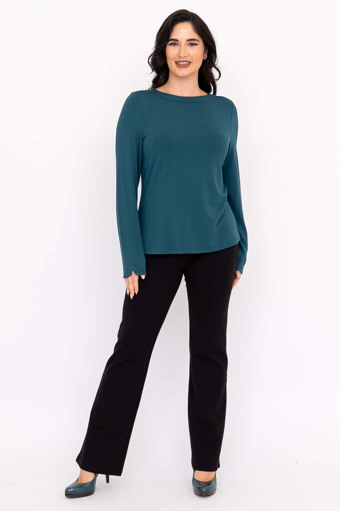 Full body view of woman in teal boat neck top and black pants