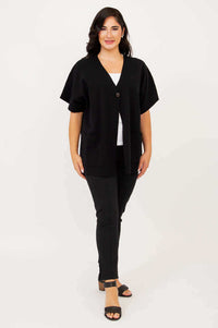 Full body front view of woman in a black cotton cardigan with cropped sleeves and relaxed fit