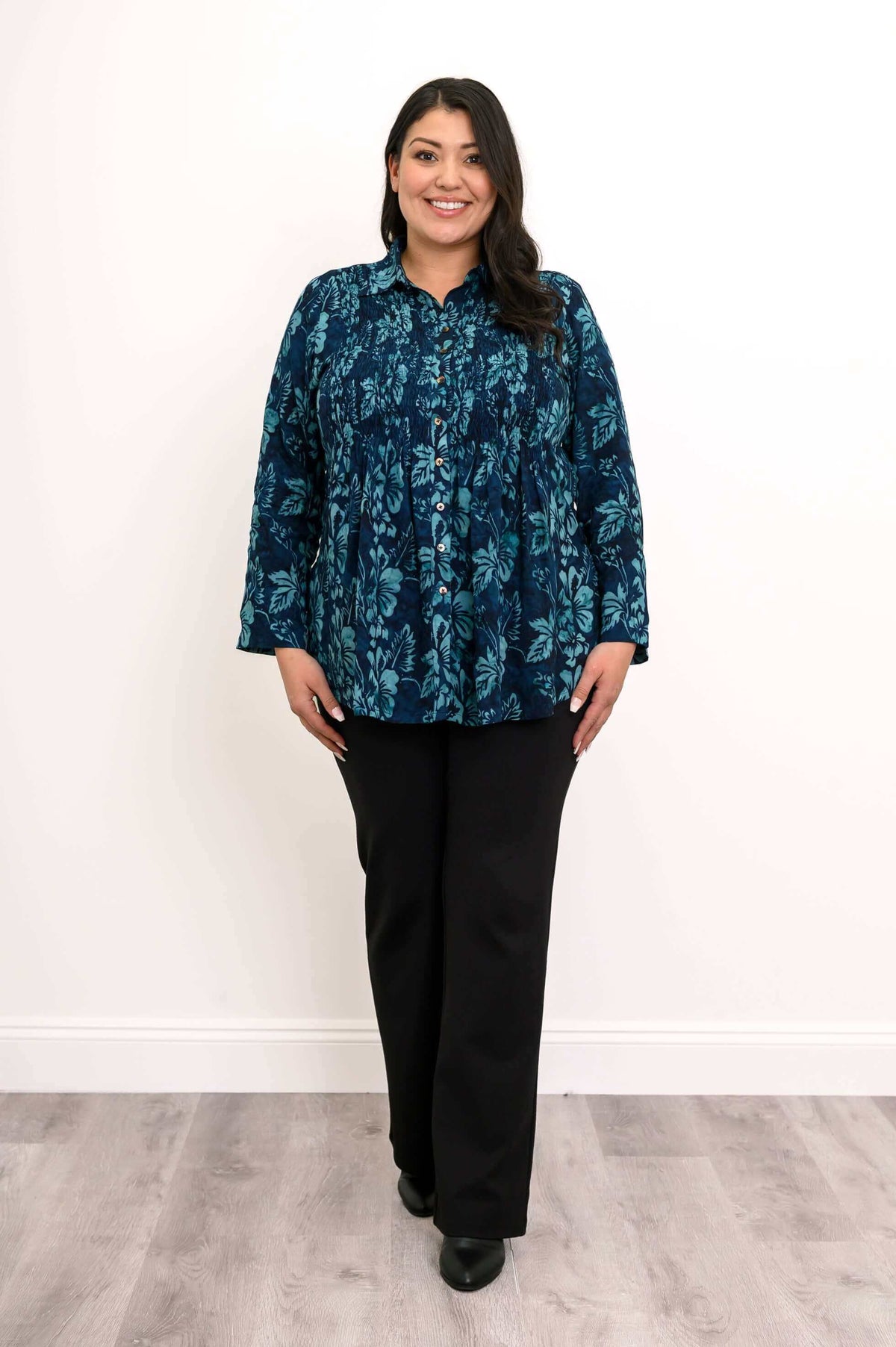 Full view of model in blue floral smocked shirt and black pants
