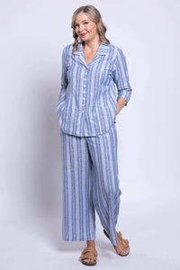 Full outfit view of model in blue striped button-up blouse and matching pants, hands in pockets