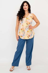 Full body view of woman in sleeveless bird print top and blue pants