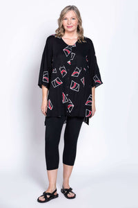 Full body view of a woman in a black button-front tunic blouse with red and white patterns