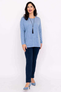 Full body angled view of woman in light blue pullover sweater and navy pants