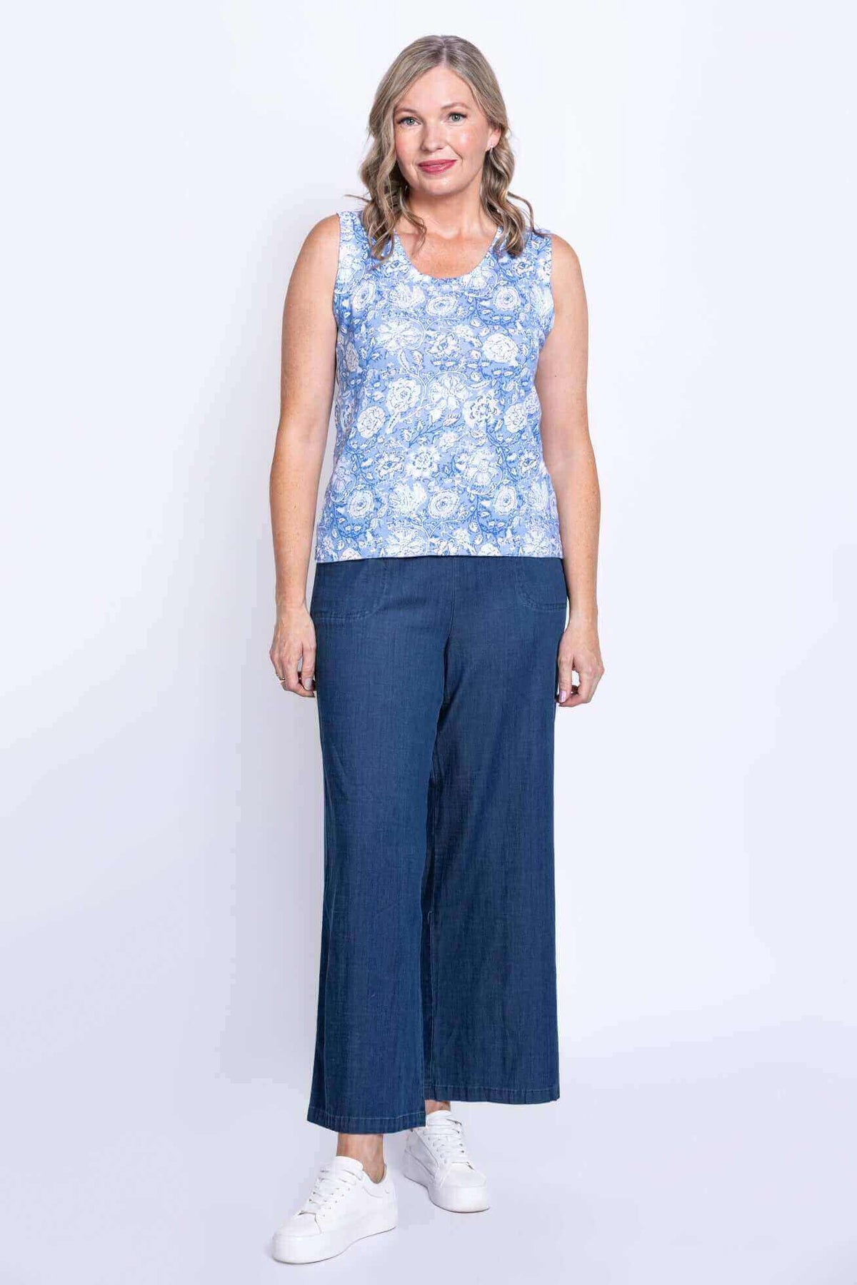 Full body front view of woman in blue floral tank and wide leg blue pants