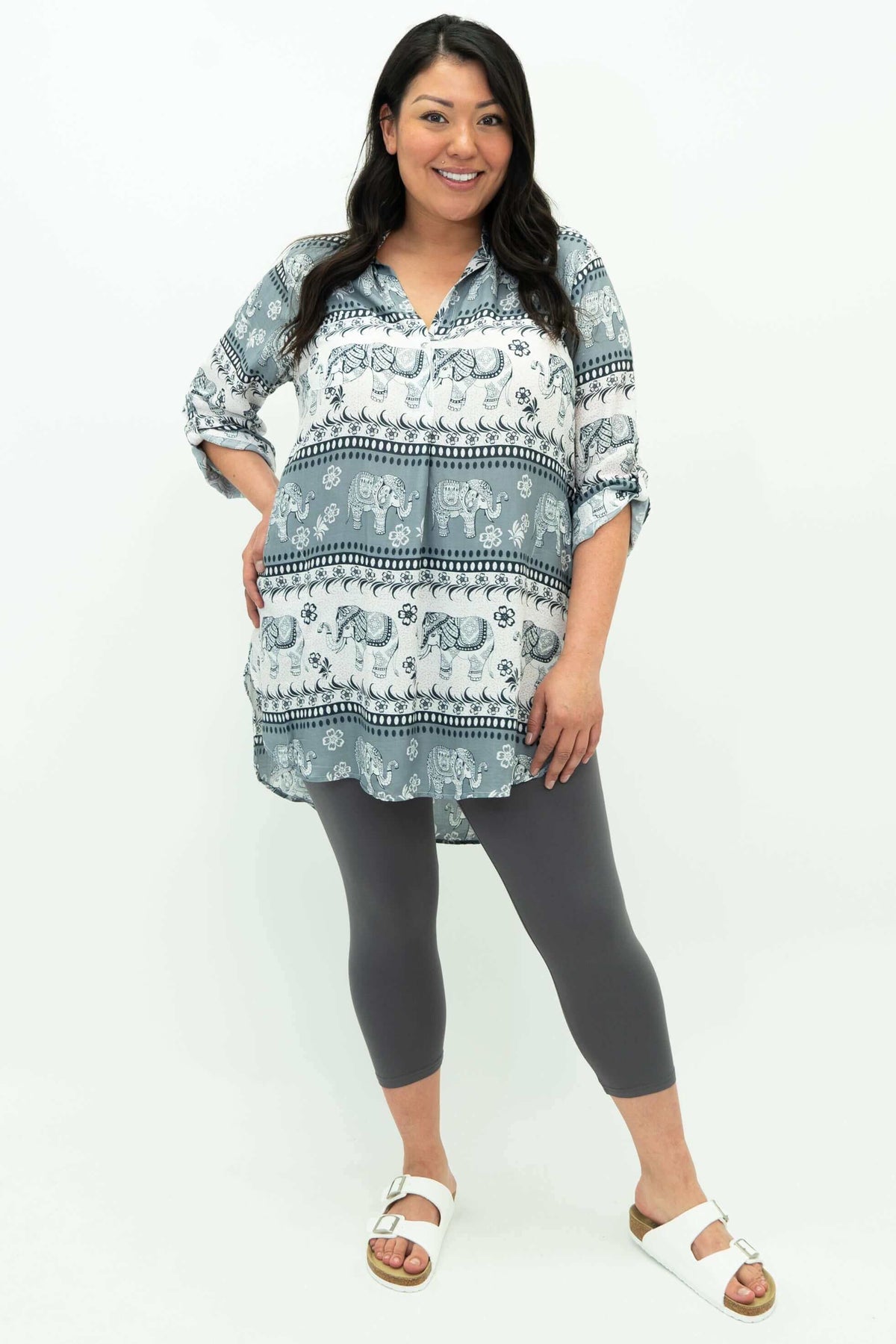 Full body view of woman modeling elephant print tunic and grey leggings