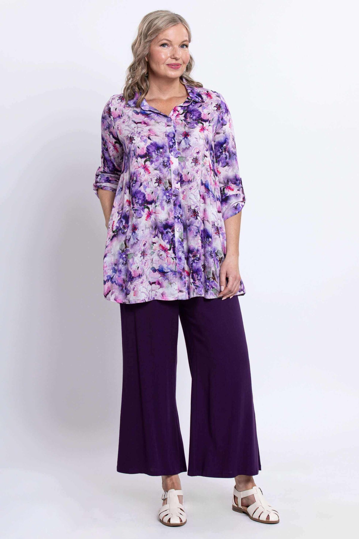 Full view of woman in floral tunic top paired with purple wide-leg pants