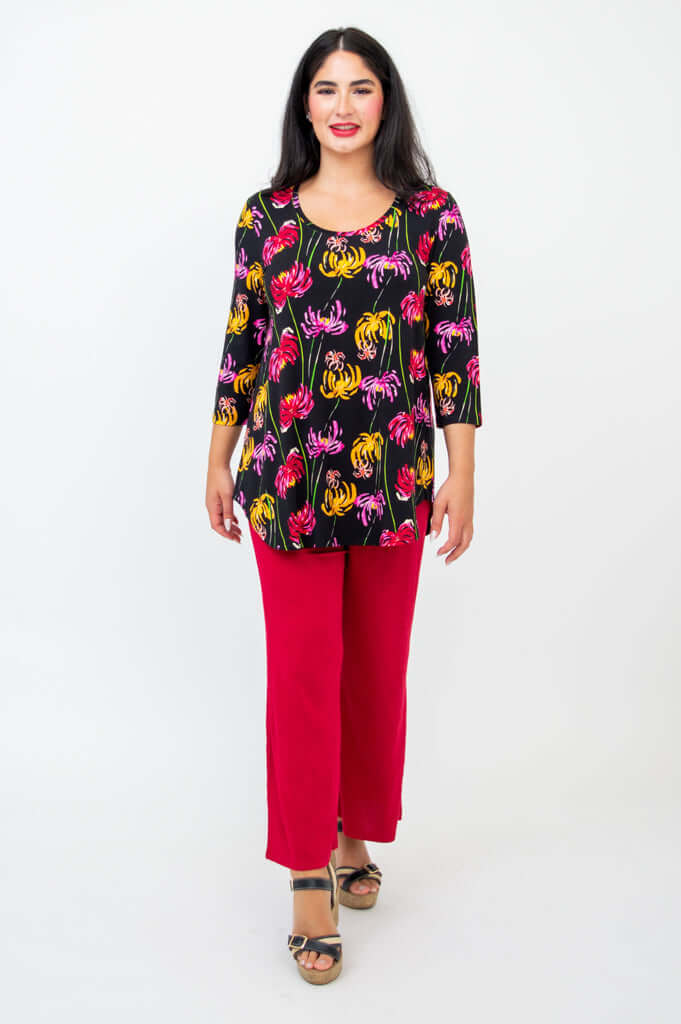Full body front view of model in black floral print top and red wide-leg pants