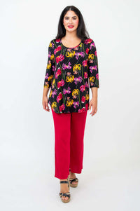 Full body front view of model in black floral print top and red wide-leg pants