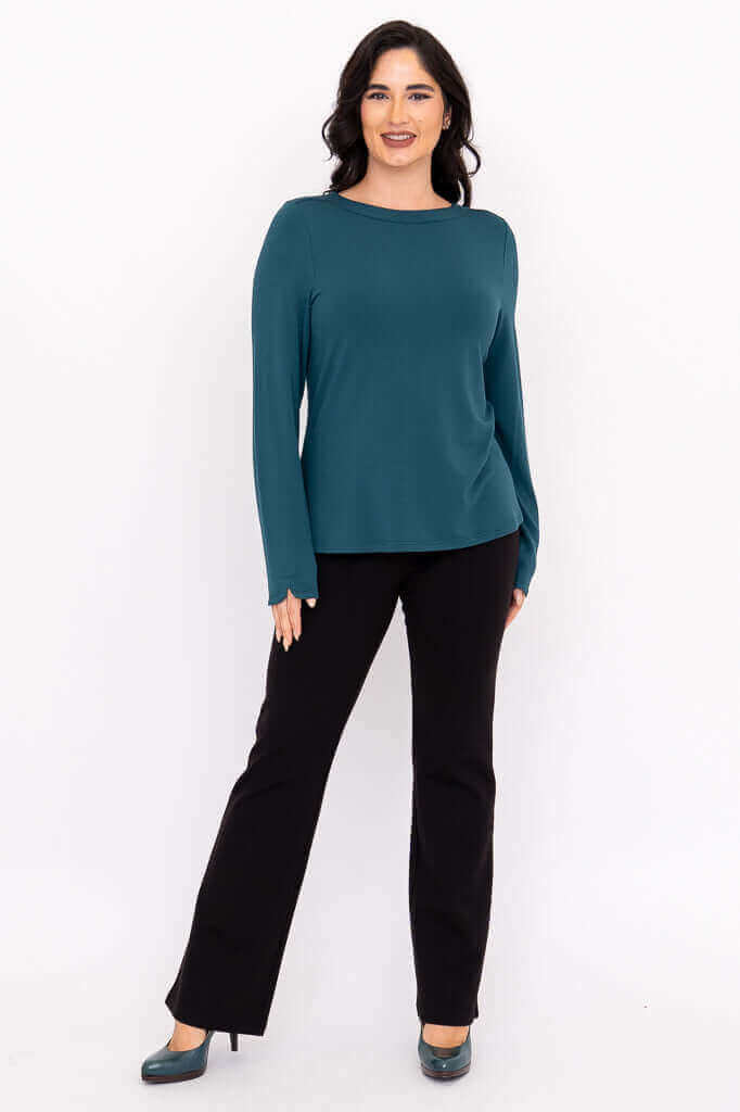 Full body front view of woman modeling teal Mona boat neck top with black pants