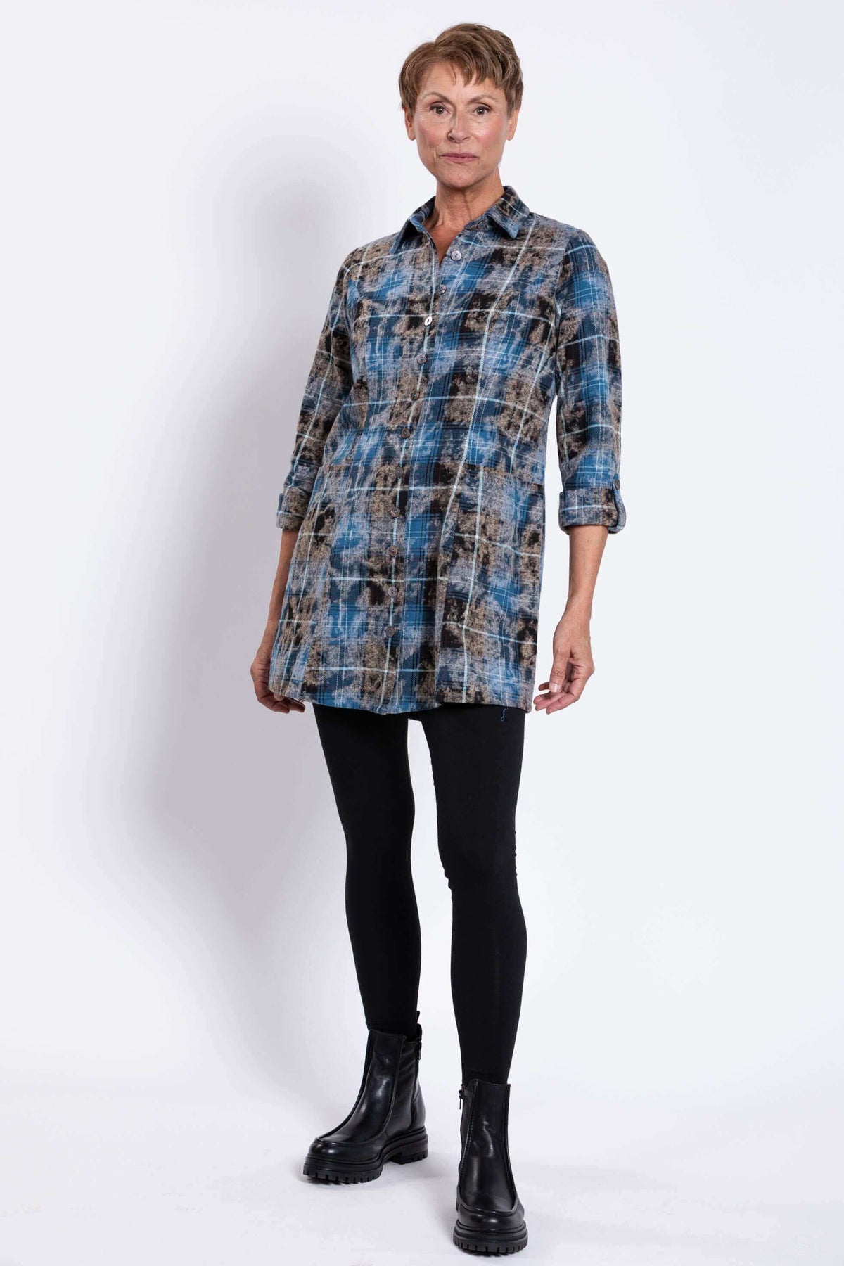Full body front angled view of woman modeling blue plaid flannel tunic with black leggings