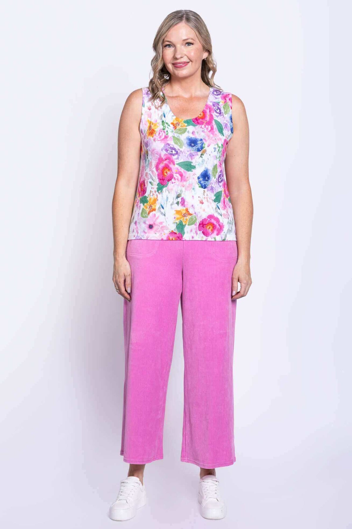 Full body view of woman in floral tank top and pink wide-leg pants, facing forward