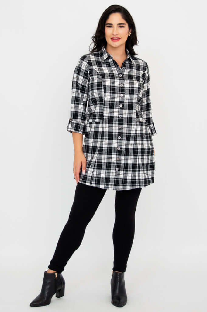 Full body front view of model in plaid flannel tunic paired with black leggings and ankle boots