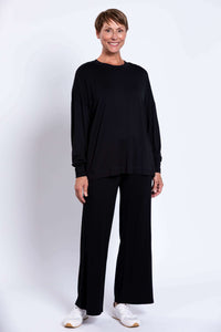 Full body front view, model in relaxed black crew neck top and wide-leg pants
