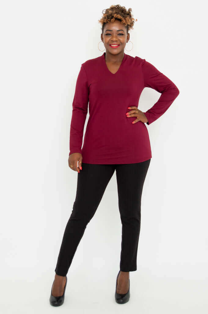 Full body front view of a woman in a burgundy V-neck long sleeve top and black pants