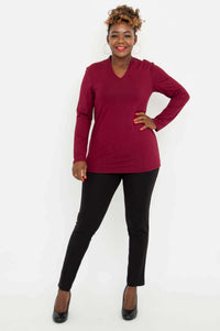 Full body front view of a woman in a burgundy V-neck long sleeve top and black pants