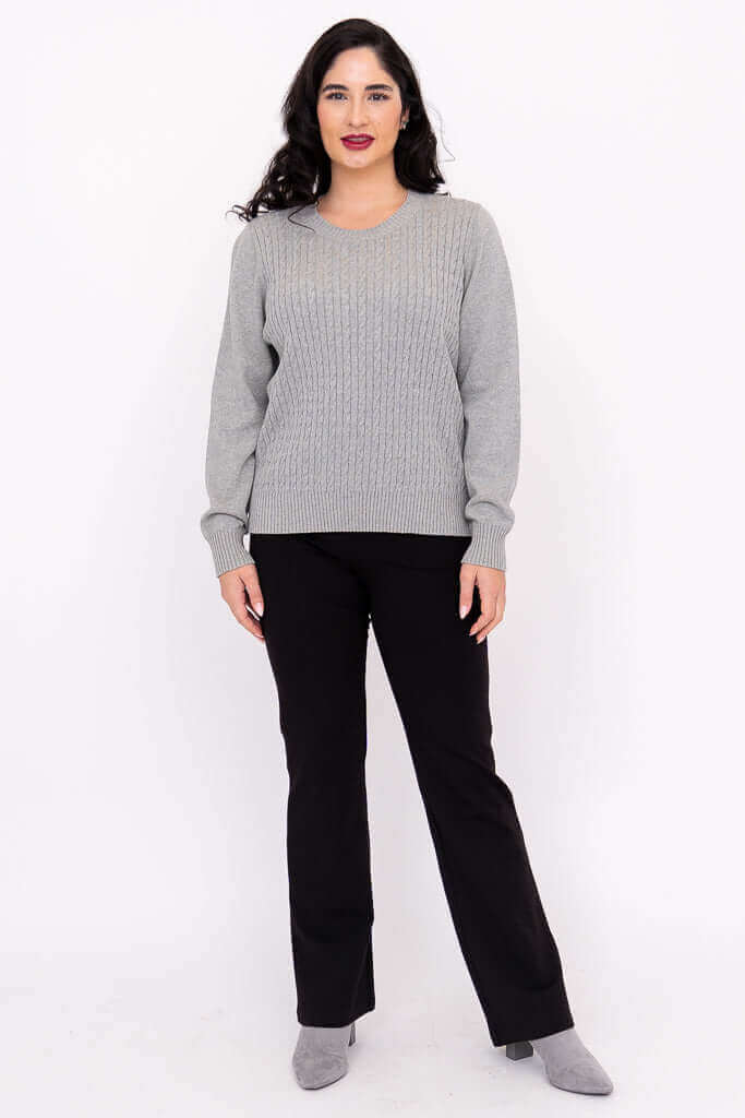 Full body front view of woman in grey cable knit sweater and black pants