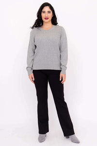 Full body front view of woman in grey cable knit sweater and black pants