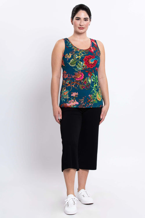 Full body front view of woman in teal floral tank top paired with black pants