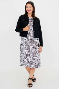 Full body view of a woman in a black cropped jacket paired with a white printed midi dress