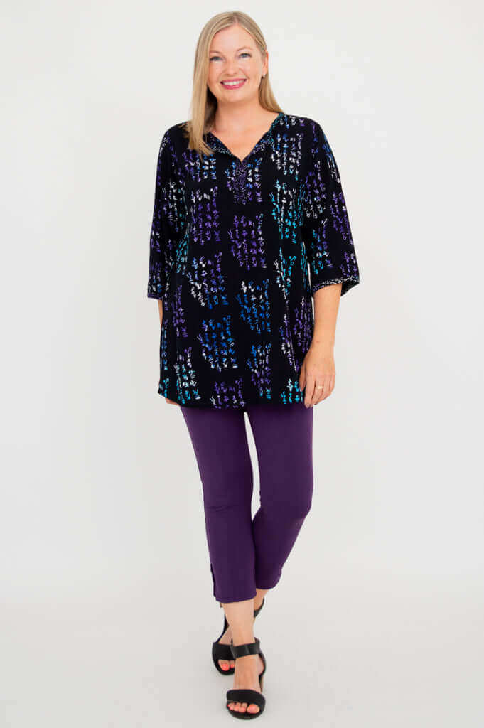 Full body front view of woman wearing black batik blouse and purple pants