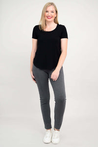 Full body front view of woman in black scoop neck tee and grey pants