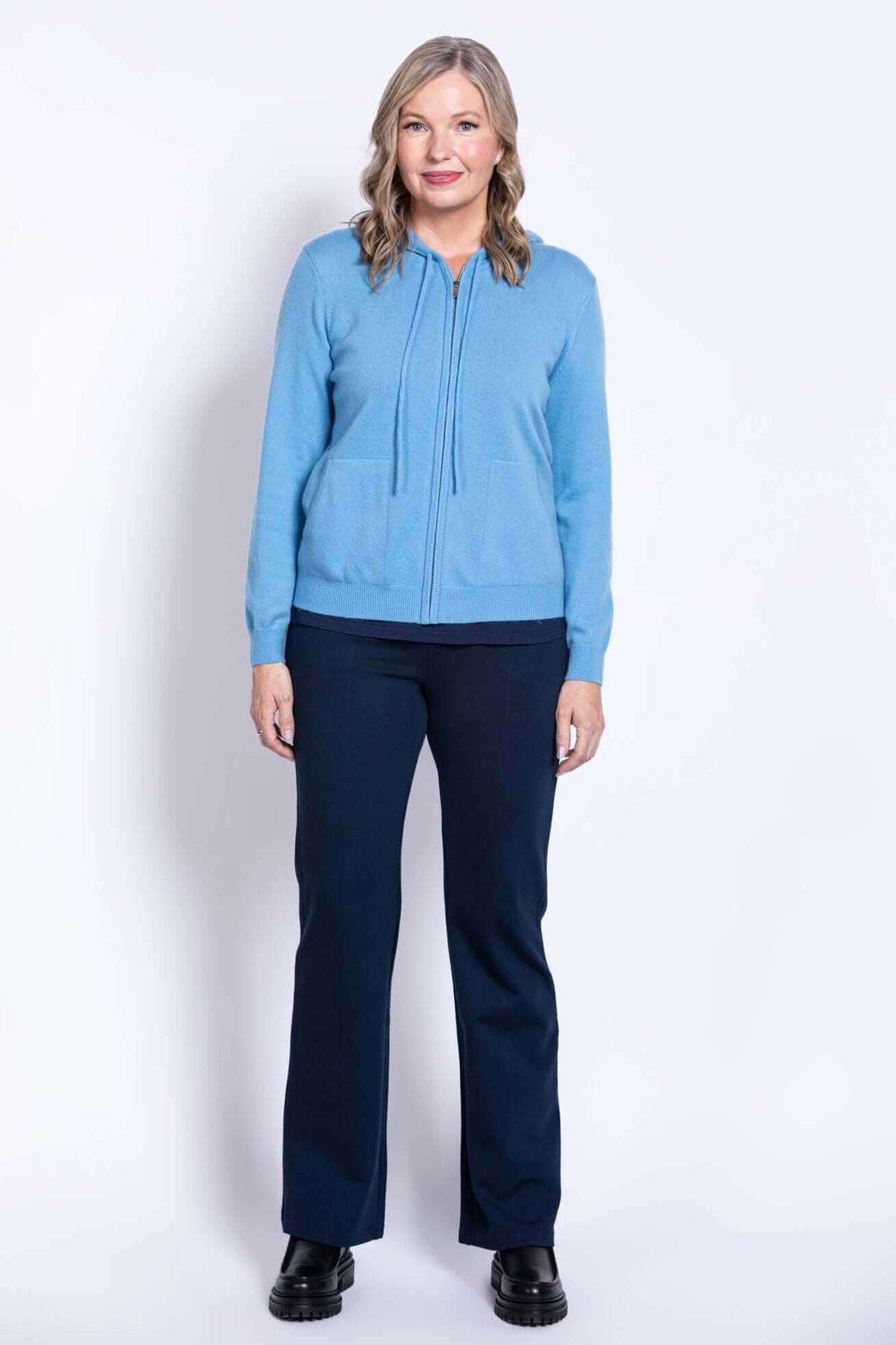 Full body front view of woman in blue hoodie and navy pants