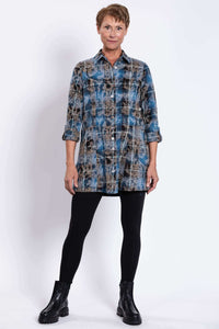 Full body front view of woman in blue plaid tunic and black leggings, facing forward