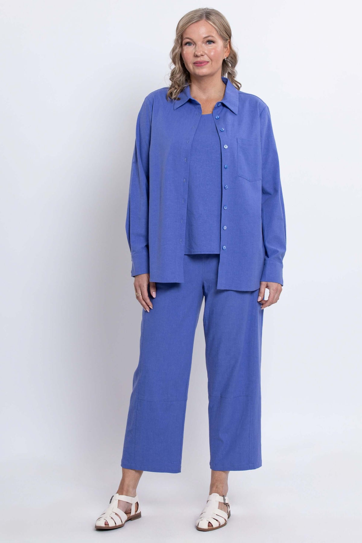 Woman standing in a blue shirt and pants set, full body, front view