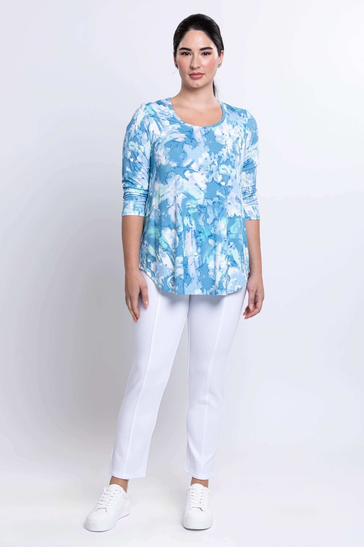 Full body front view of woman in blue watercolor bamboo top and white pants