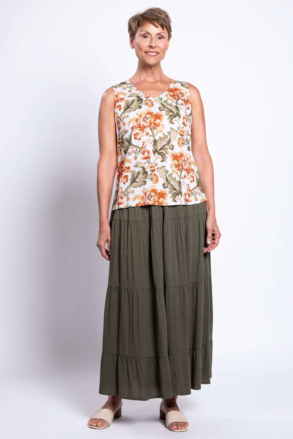 Full body front view of woman in floral sleeveless V-neck tank and olive tiered skirt