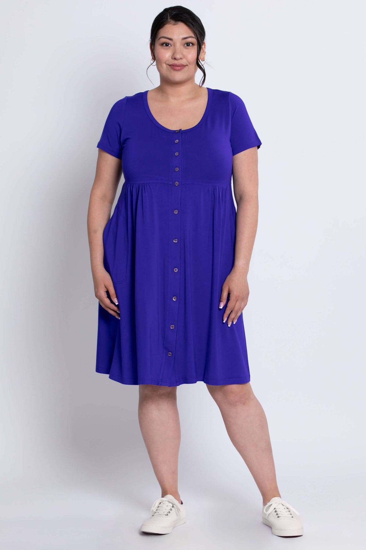 Full body front view of a model in a purple dress featuring short sleeves and button details