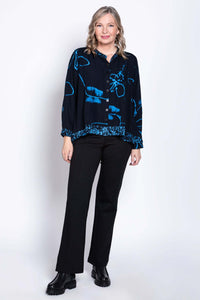 Full body front-facing image of a woman in a navy high low batik print blouse and black pants