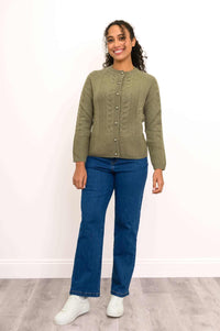 Full length view of a woman wearing an olive green cashmere cable knit cardigan sweater and blue denim jeans.