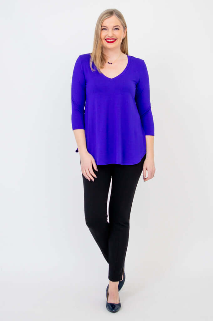 Woman modeling a purple V-neck bamboo top with black pants, full body front view