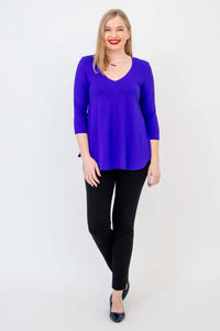 Woman modeling a purple V-neck bamboo top with black pants, full body front view