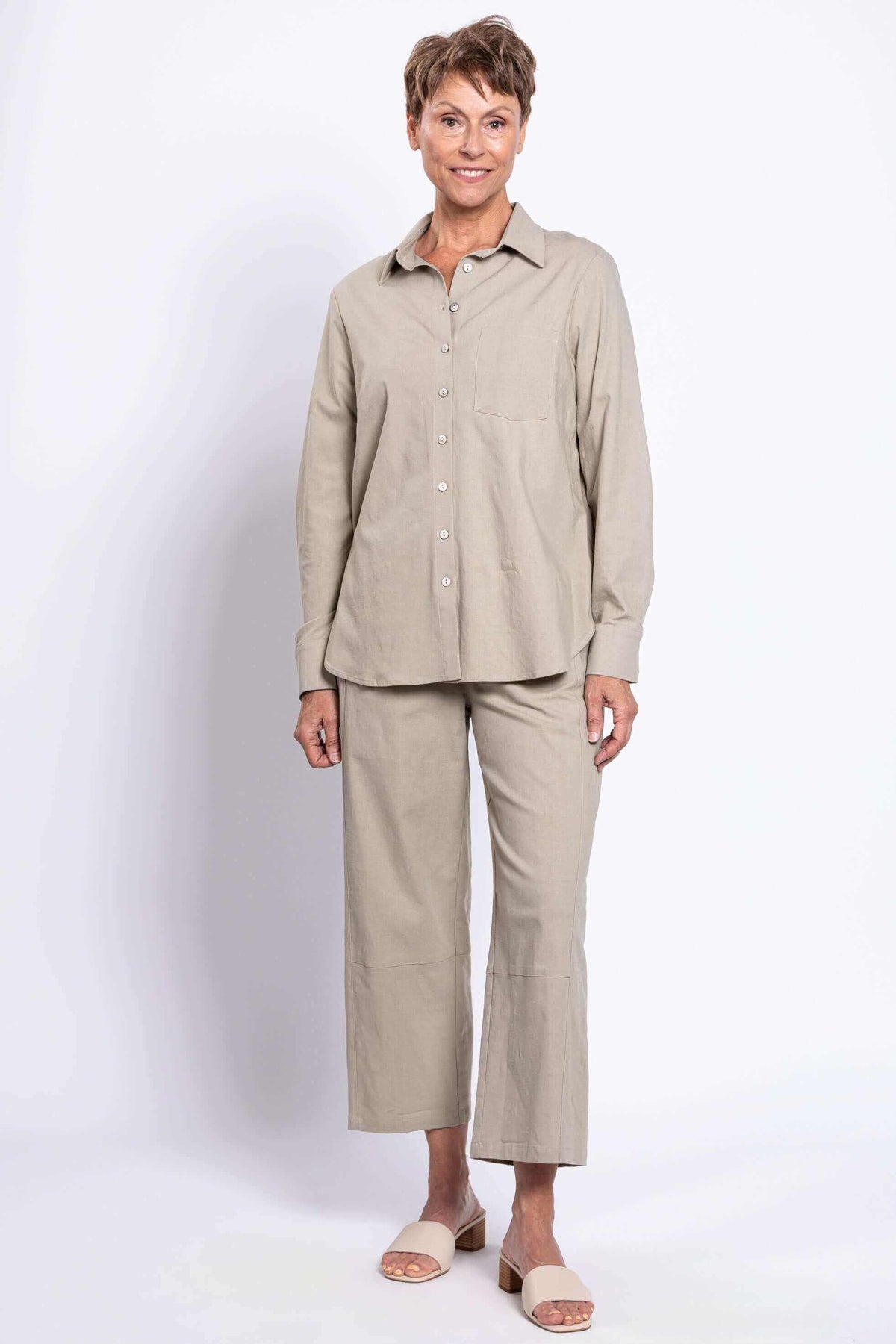 Woman smiling in sage casual shirt and wide-leg pants, full body front view