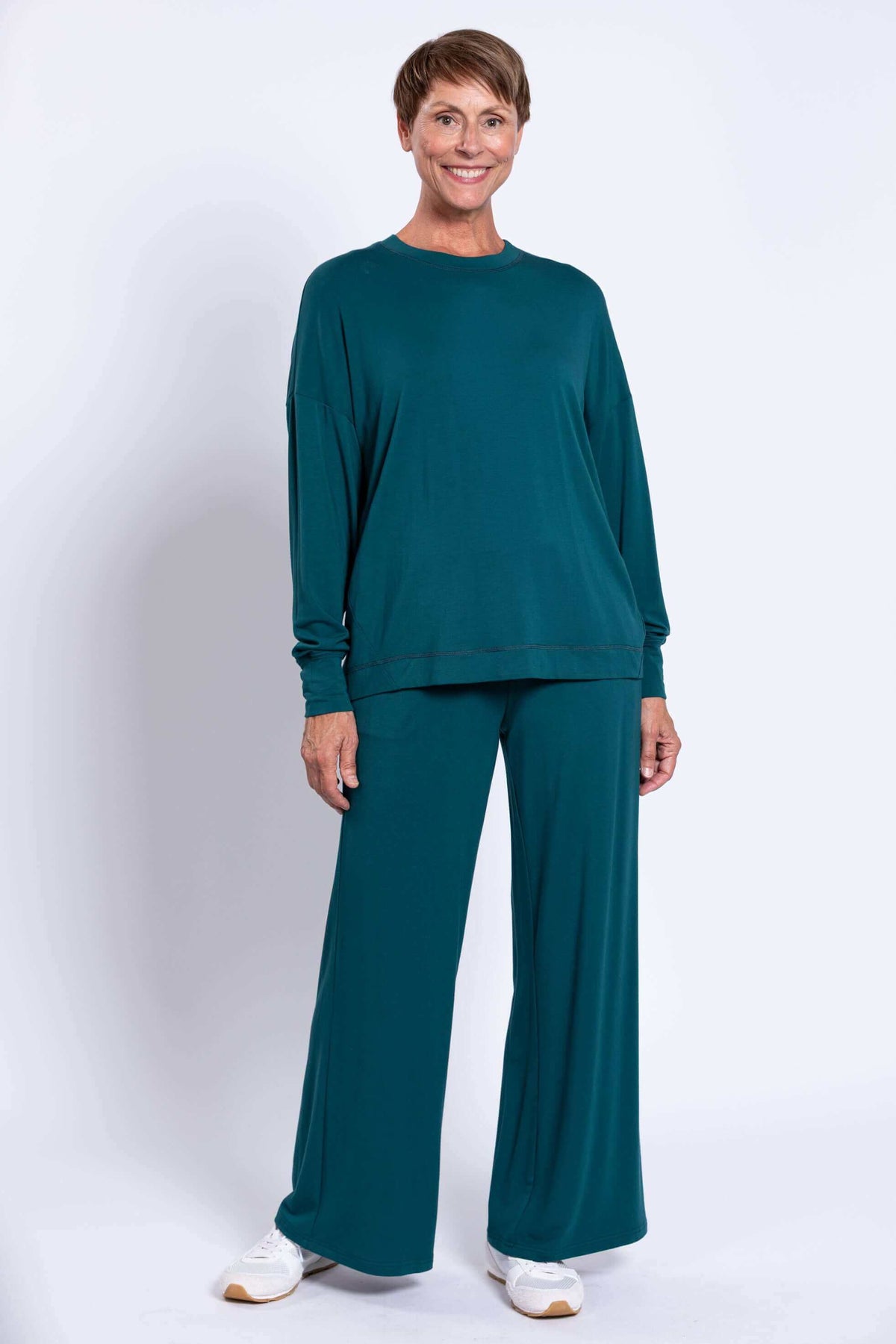 Full body front view of woman in teal drop shoulder top and wide leg pants