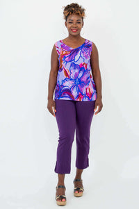 Full body front view of a woman in a colorful floral V-neck tank and purple pants
