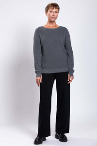 Full body front view of woman in gray shaker stitch sweater and black pants
