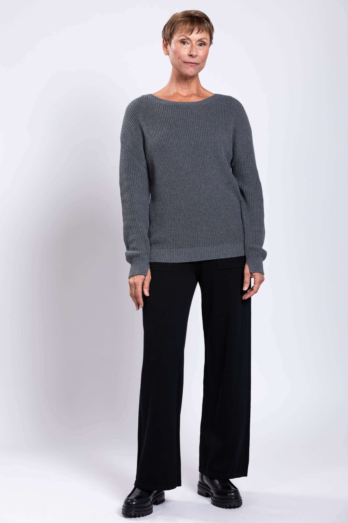 Full body front view of woman in grey cotton sweater and black pants