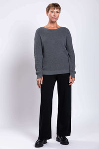 Full body front view of woman in grey cotton sweater and black pants