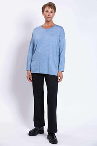 Full body front view of woman in light blue Merino sweater and black pants with boots