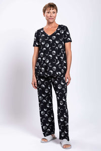 Full body view of woman in black moon phase top and pants, standing, front view